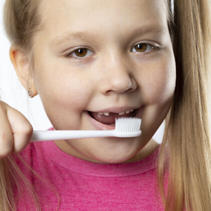 牙科有第一个成年门牙和牙刷的学龄前女孩乳牙脱落了 一颗恒牙长在张开的嘴上牙齿卫生概念牙齿刷子小