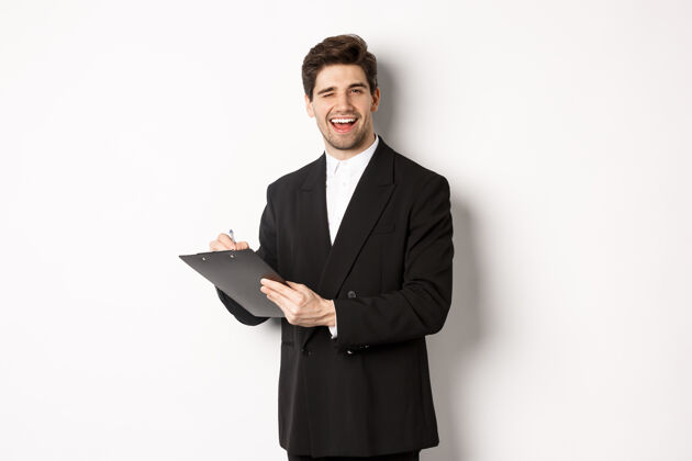 购物帅气 成功的老板穿着黑色西装 在签署文件时眨眼微笑的形象成功促销经理