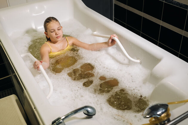 家庭一个小女孩在矿泉浴中进行这个过程患者接受矿泉珍珠浴水治疗白天美丽谎言