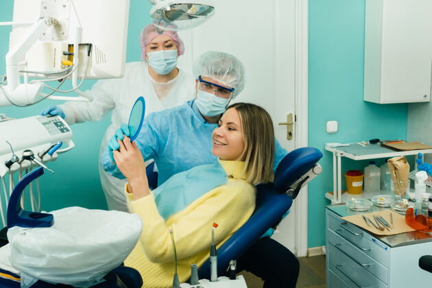 女人牙医在镜子里给病人看他的工作结果微笑牙齿治疗