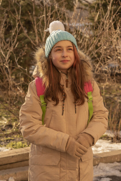 快乐快乐寂寞迷人的年轻女孩穿着暖和的衣服背着背包站在冬天的森林或公园里人时尚青少年