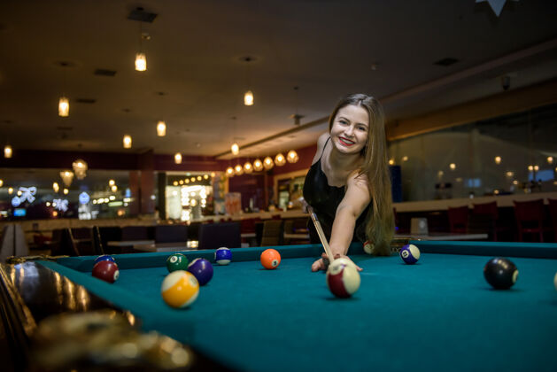 酒吧年轻漂亮的女人在酒吧打台球娱乐提示挑战