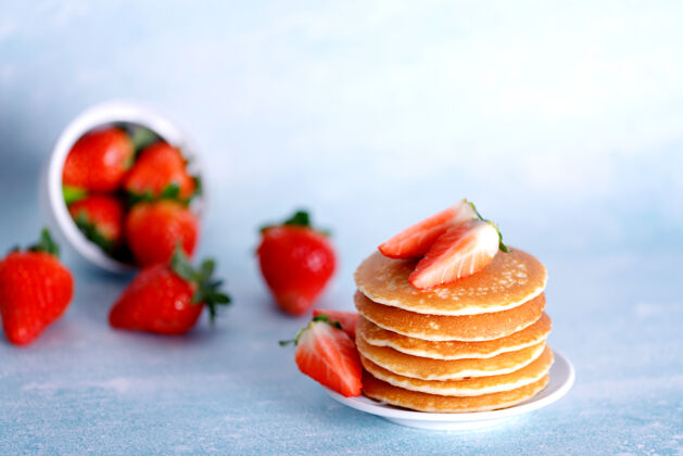 堆美味的美国薄饼 白色盘子上有草莓 蓝色背景面包房草莓甜点
