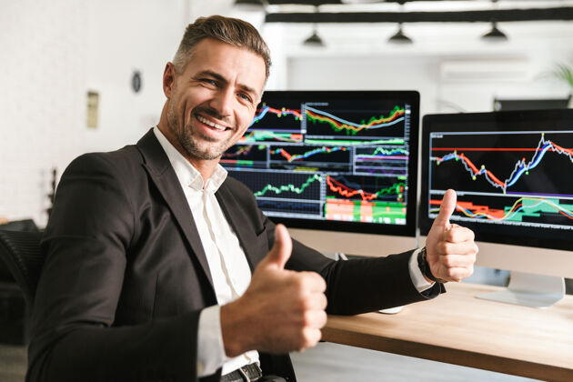 男人30多岁的快乐商人穿着西装在电脑上工作 屏幕上有图形和图表工作场所统计室内