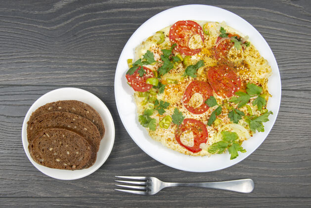 午餐木桌上的白色盘子里放着香草和蔬菜的煎蛋卷开胃菜烹饪晚餐