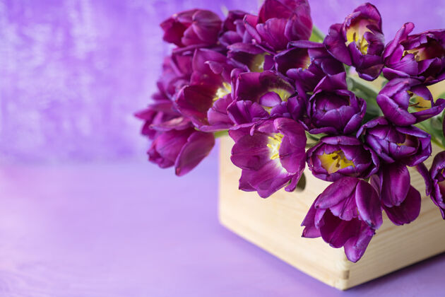 篮子漂亮的紫色郁金香放在紫色桌子上的木篮子里复活节郁金香白天