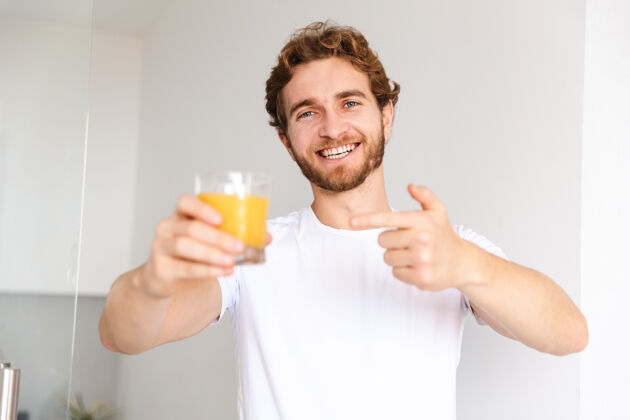 白种人一个留着胡子的帅哥在家喝果汁 竖起大拇指放松成人维生素