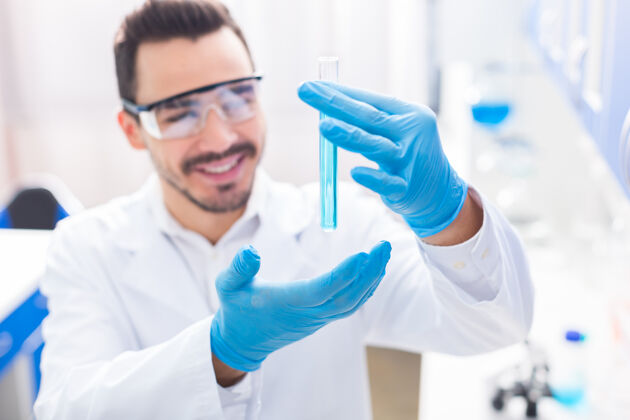 临床成功的实验选择性聚焦男性手持小瓶装满液体和男子戴上安全眼镜和咧嘴笑成功研究实验