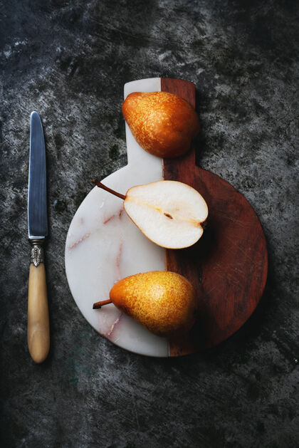 健康新鲜的土生土长的梨子放在半块大理石和带有乡村小刀的木制砧板上顶视图平铺有机美味多汁