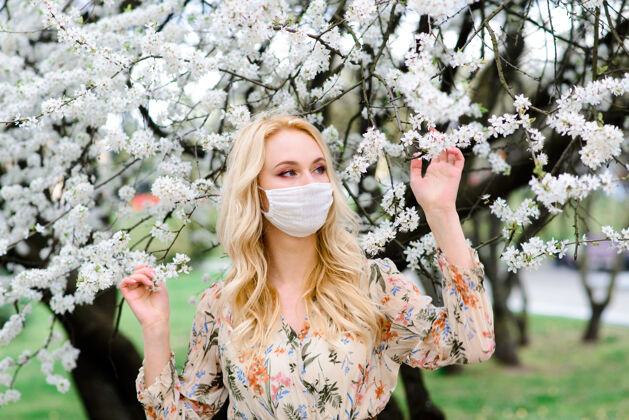 女孩女孩 年轻的女人在春天的时候脸上戴着一个无菌的医用防护面具花园.空气污染 病毒 大流行冠状病毒概念面具户外年轻