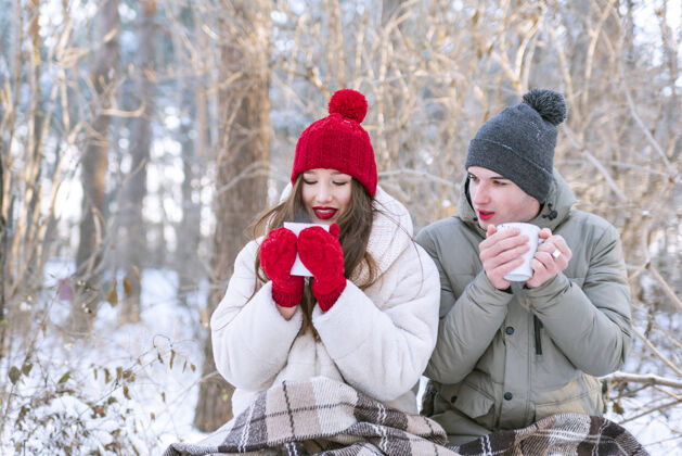聚会这对年轻夫妇在公园野餐冬季恋人在森林里喝茶帽子公园茶