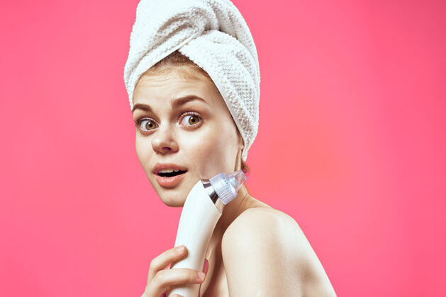 身体欢快的民族妇女用毛巾在她的头上按摩手皮肤护理水疗护理粉红色的背景清洁药面膜