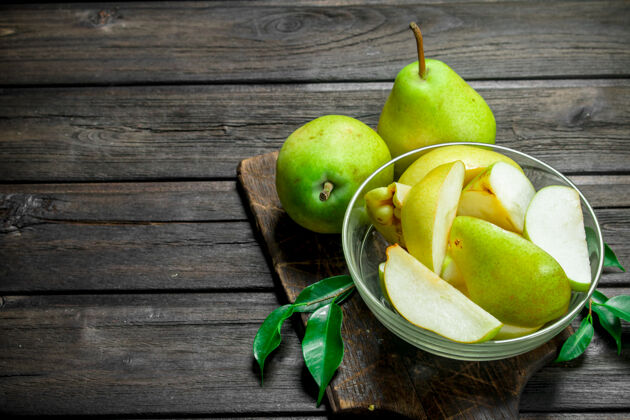 梨成熟的梨放在砧板上的碗里 叶子放在木桌上成熟叶美味