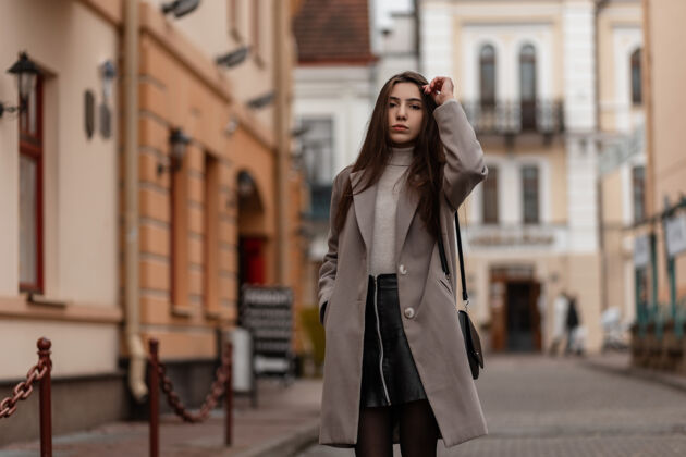 外套一个棕色长发 穿着时髦外套的年轻女子在城里摆姿势手提包女孩都市