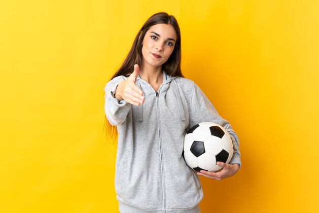 运动员年轻的女足球运动员在黄色握手成交好比赛握手信任