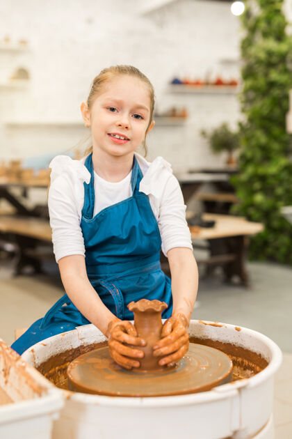 碗漂亮的小女孩在陶艺作坊里做陶罐粘土创作爱好