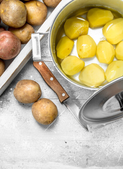 收获把去皮的土豆放在锅里 把生土豆放在乡村餐桌上的托盘上健康碳水化合物团体