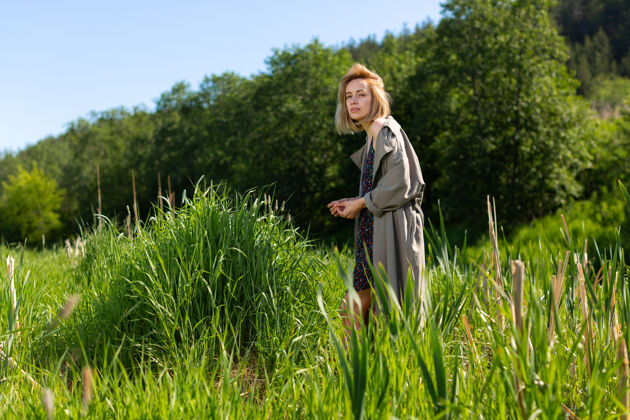 走路一个穿着灰色斗篷的女人站在高高的草地上女人年轻自然