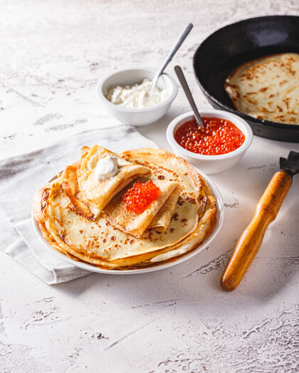 酸传统的俄罗斯布利尼薄煎饼与红色鱼子酱 新鲜的酸叠在一个盘子里奶油奶油俄罗斯传统节日膳食.俄语食物 俄罗斯厨房早餐热顶视图