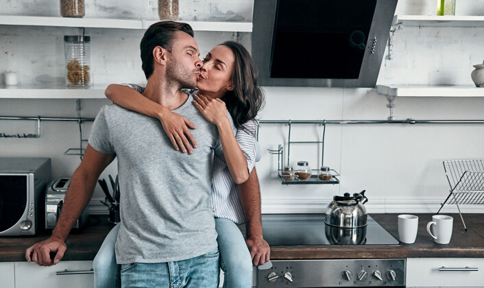 拥抱浪漫的年轻情侣在床上接吻厨房漂亮年轻的女人和英俊的男人站在明亮的现代厨房里享受着一起的时光厨房房子公寓