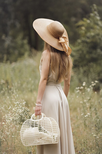 花一个时髦的女孩拿着一篮子田野穿过草地花年轻天生的金发女人女孩女性草地