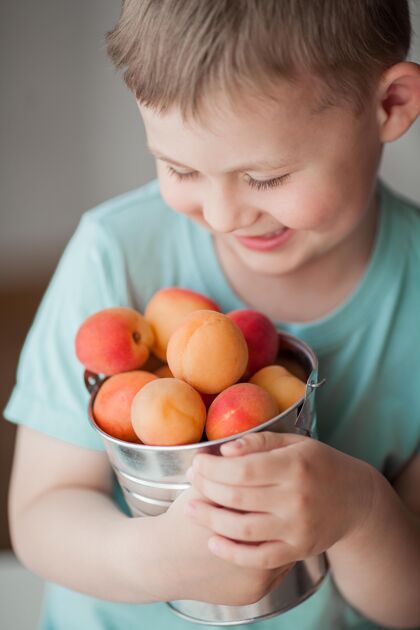 可爱一个4岁的可爱小男孩正在吃桶里的多汁杏子自然健康快乐