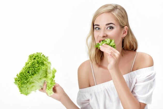 健康一个穿着白衬衫的金发美女在白衬衫上吃着新鲜的蔬菜沙拉背景.健康还有节食年轻白色体重