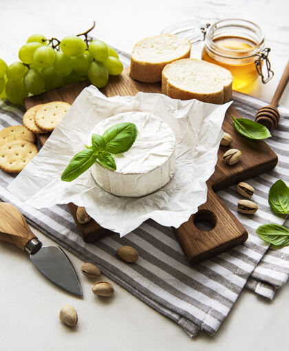 瑞士食品白色桌面上的切菜板上的卡门贝尔奶酪 葡萄 坚果和蜂蜜的特写镜头产品卡门贝尔食品