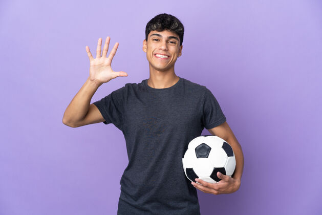 球年轻的足球运动员在孤立的紫色背景上用手指数着五手指比赛数字