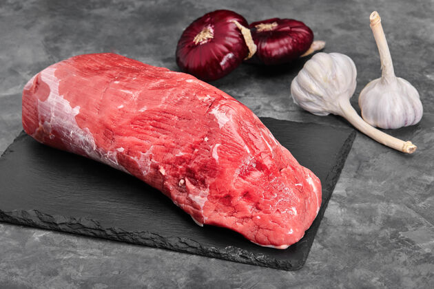 牛腰肉鲜肉和生肉整片牛排排成一排 准备在黑色黑板的背景下烹调生的餐桌蔬菜