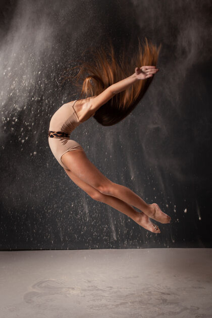 舞蹈一个体育女孩体操运动员在演播室里穿着灰色的飞扬的面粉身体艺术芭蕾舞演员