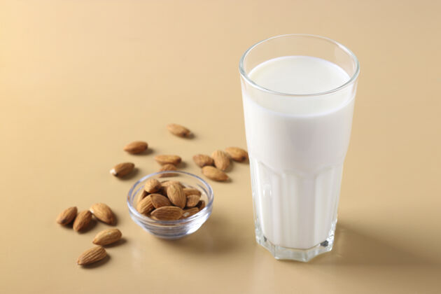 复制空间米色表面有新鲜杏仁牛奶和杏仁的玻璃杯 健康纯素牛奶替代品 水平格式 文本空间 特写玻璃蔬菜生物