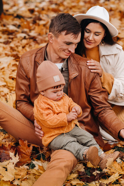 宝贝爸爸和妈妈带着儿子在秋天的公园里散步一家人在金秋的自然公园里散步男人健康男孩