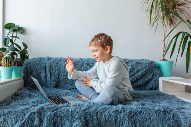 冠状病毒小男孩有视频通话 在线课堂上的笔记本电脑电子学习 远程学习 远程沟通的概念挥手聊天学习