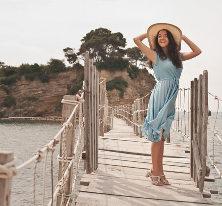 旅游戴着夏帽的年轻女子在桥上摆姿势美丽放松假日