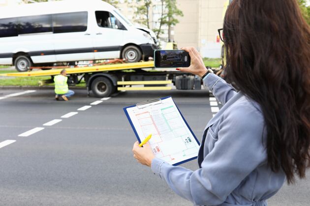 助理手里拿着文件的女人在电话里给失事的汽车拍照失事汽车城市