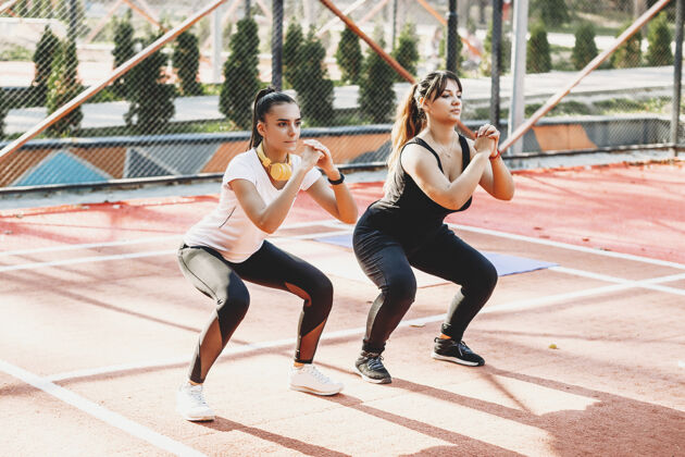 年轻一个女人和她的女朋友在户外运动场锻炼减肥 一边听音乐朋友健康形状