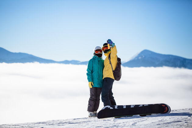站立滑雪者在山上用智能手机拍照情人图片假期