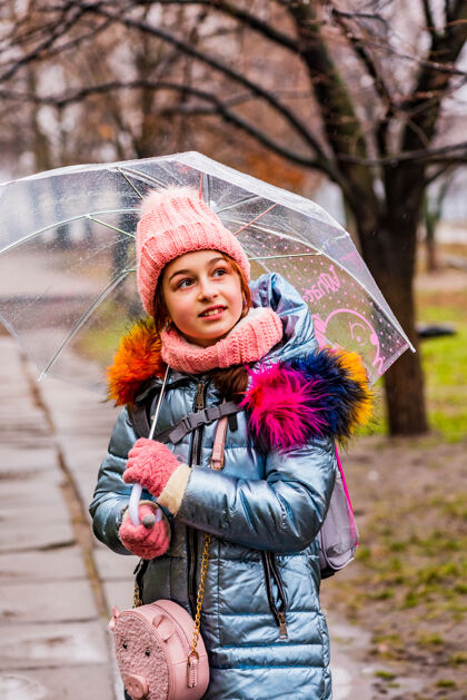 寒冷金发碧眼的女孩穿着夹克带着透明的雨伞在外面的雨中御寒外套女孩户外