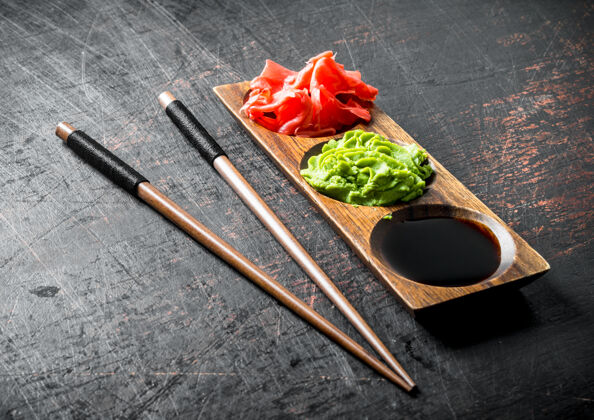 食物酱油 生姜和芥末放在木架上筷子.on黑暗的乡村背景菜肴切亚洲菜