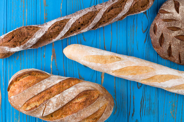 分类新鲜烤面包的顶视图照片在涂了漆的蓝色木桌上混合面包品种
