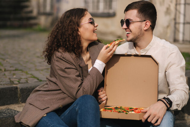 情侣坐在室外楼梯上吃比萨饼的年轻夫妇电话意大利女人