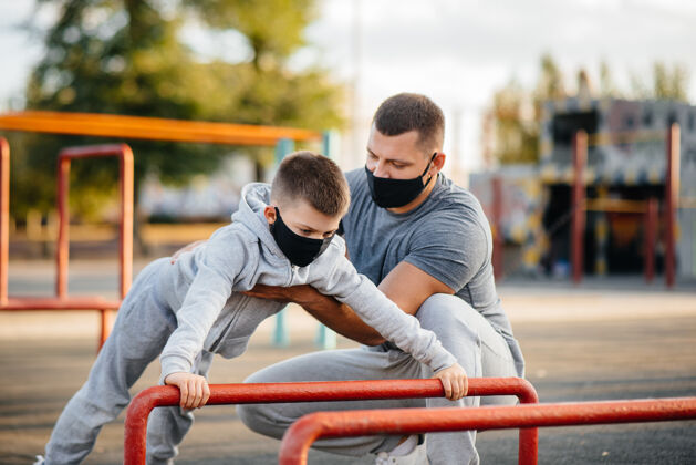 训练日落时分 父子俩戴着面具在运动场上运动护理年轻健康