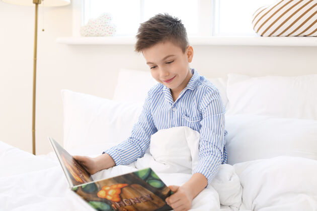 睡衣可爱的小男孩在家读睡前故事阅读可爱兴趣