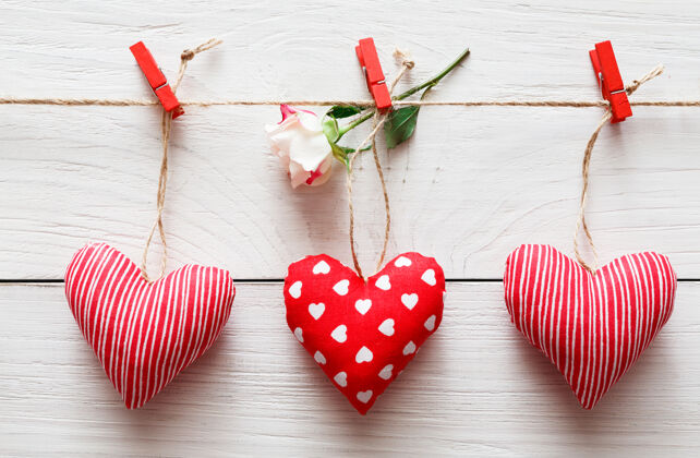 卡片情人节用红纸做的心形在衣柜上画边框 乡村木板上画玫瑰花庆祝木头衣夹
