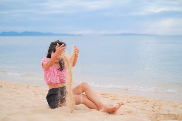 乐趣坐在海边沙滩上的亚洲女人海她在暑假的休息日玩得很开心女人海滩沙子