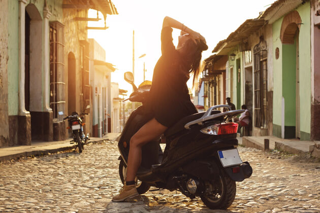 旅行年轻的女旅行者开着滑板车在老城区的街道上摩托车城市户外