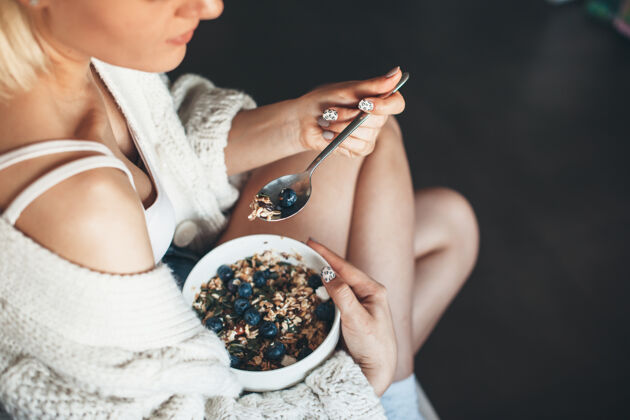 女性上图是一位穿着针织毛衣的金发女士 她有着健康的饮食习惯 坐在地板上吃麦片保健室内吃