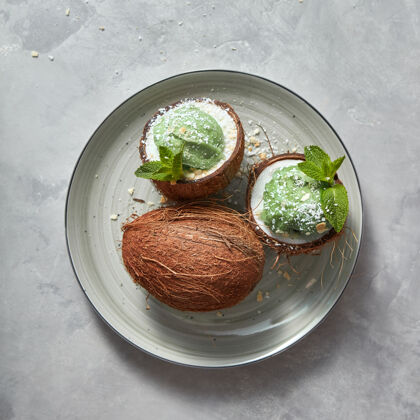 刷新两份椰子和自制的绿薄荷冰淇淋和整个椰子放在一个盘子里放在一张灰色的桌子上 复制空间…夏天的概念饮食奶油薄荷