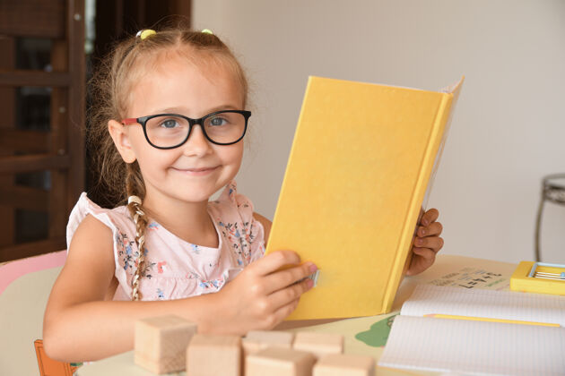 学校幼儿园漂亮女学生坐在教室里看书的画像教科书很少坐在书桌旁看书的女孩书籍小学生房子